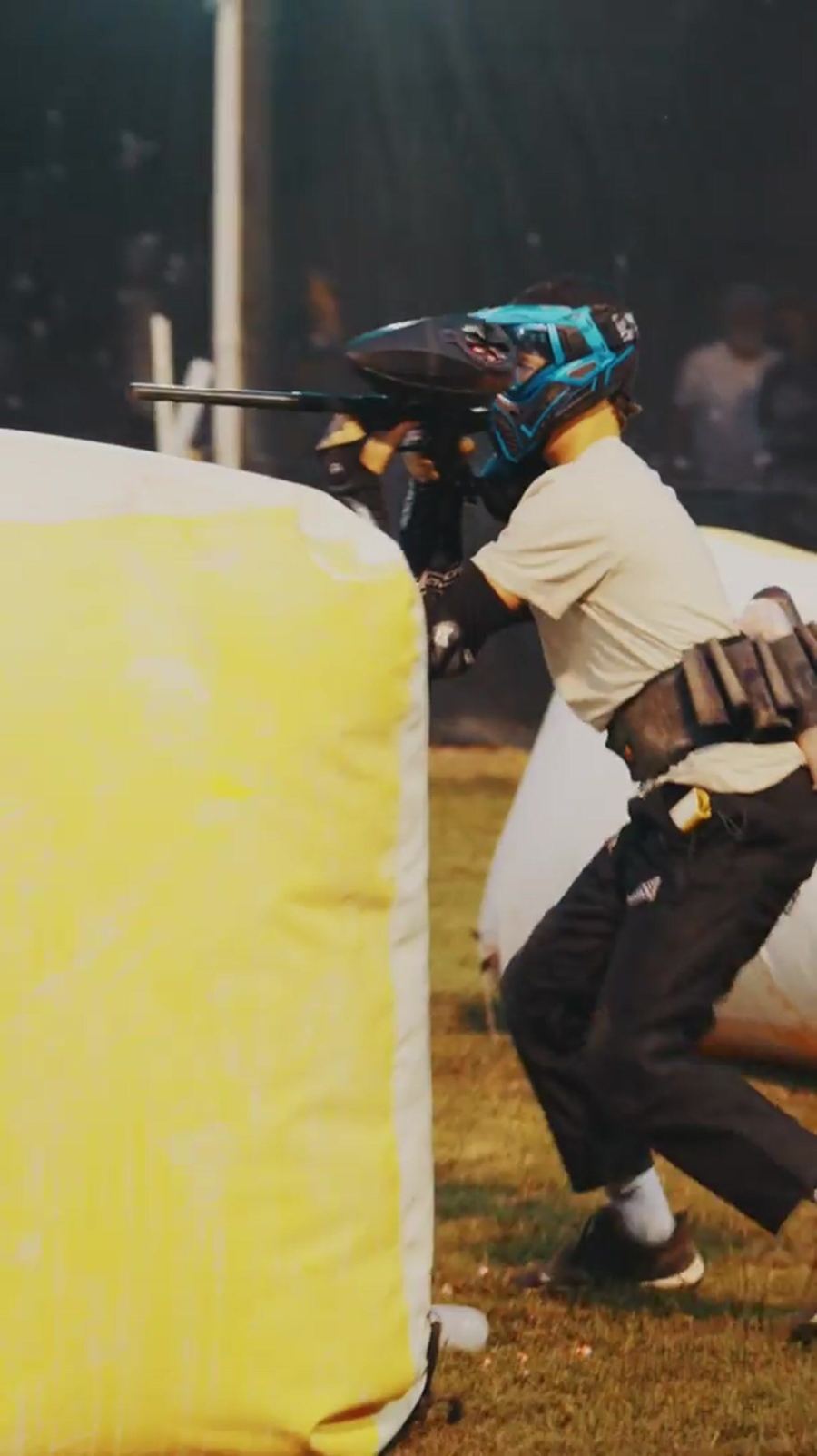 Player aiming over a yellow inflatable bunker on the speedball field