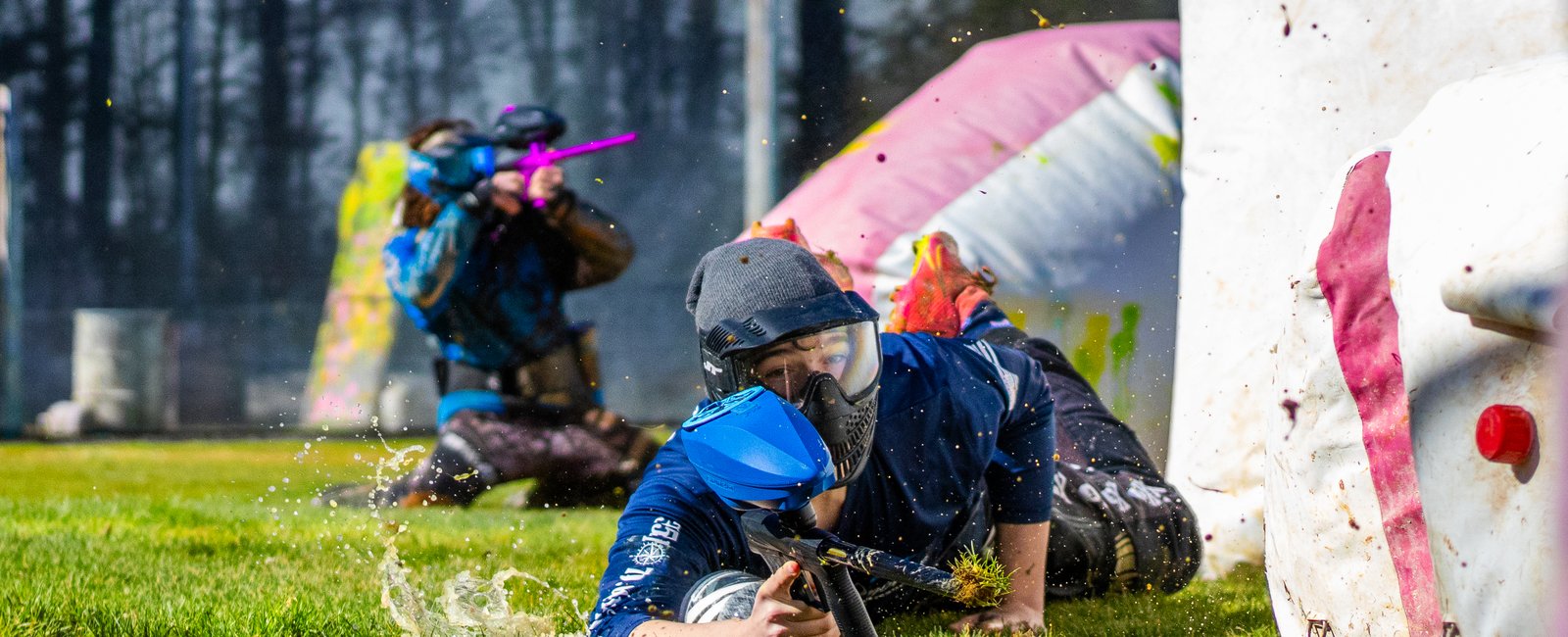 Player diving prone through the grass mid-firefight on the speedball field