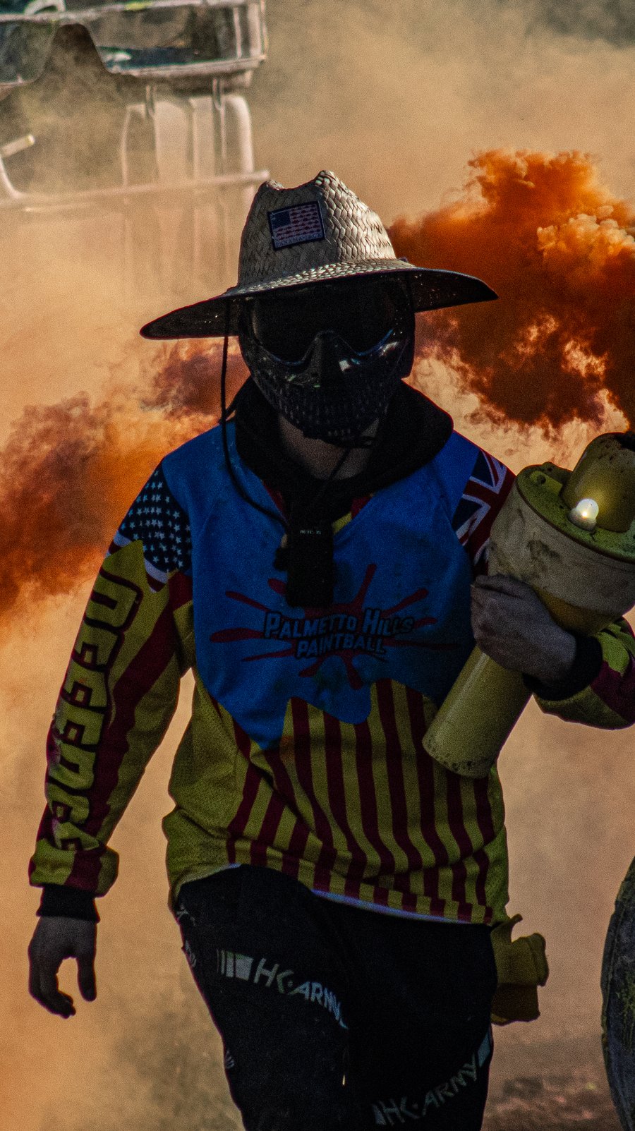 A Palmetto Hills referee in a straw hat walking through orange smoke